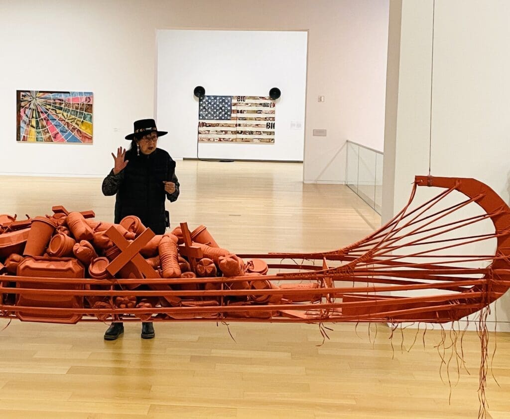 The artist explains the meaning of the red ochre colored canoe sculpture. (Photo by Courtney Dabney)