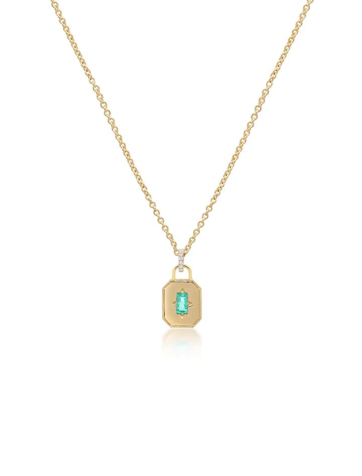 This State Property Spade Warisan Minor Emerald Necklace features an adjustable 18K yellow gold chain and an octagonal charm set with a bright green baguette emerald at its center. 