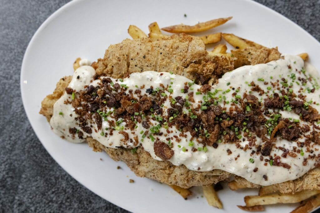 The Rub's nightly chicken fried steak —currently on the Memorial Green location's  lunch menu is made with the
ribeye cut topped with bacon studded white gravy and French fries. (Photo by Lauren Holub )