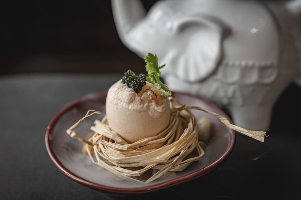 "Eggcellent" appetizer, hollowed eggshells filled with a light Tom Yum bisque mousse with crispy shrimp and a touch of caviar. Photo by Sean Rainer.