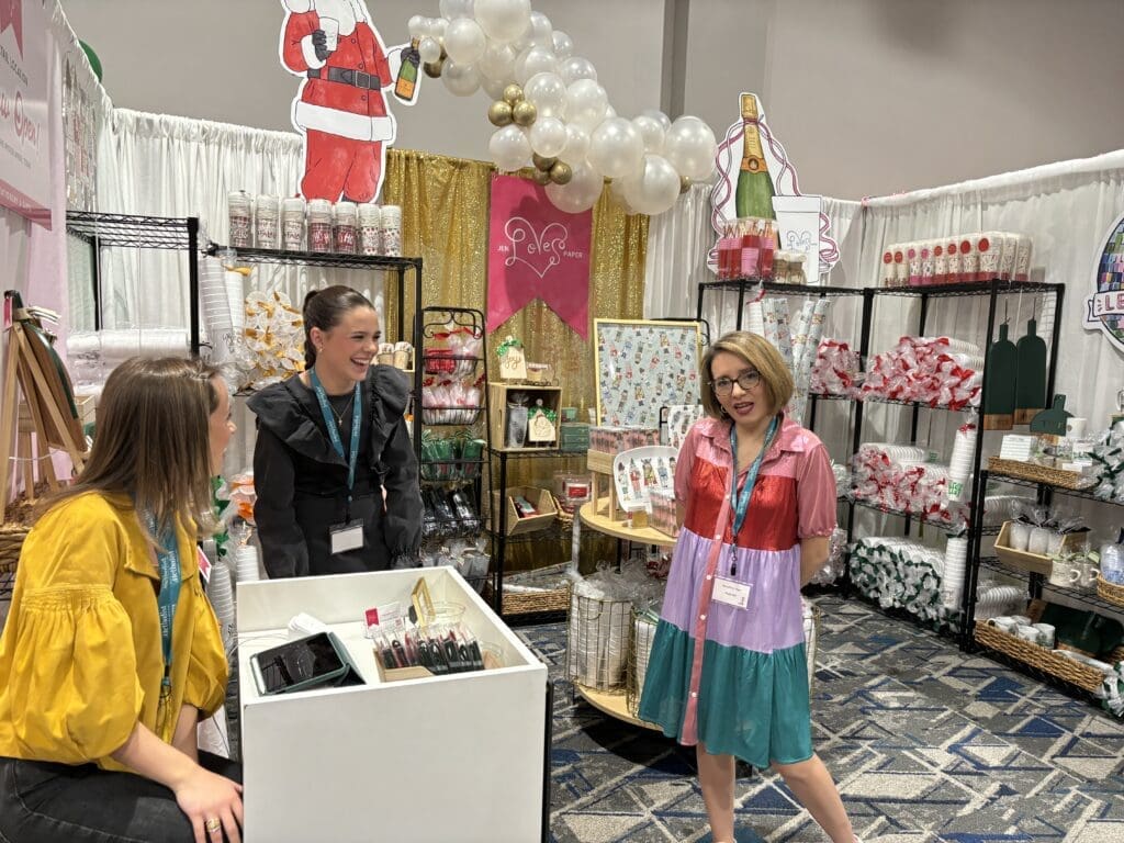 Owner Jen McDonald and her staff enjoy a fun moment in her booth at Holly Jolly. (Photo by Laura Landsbaum)