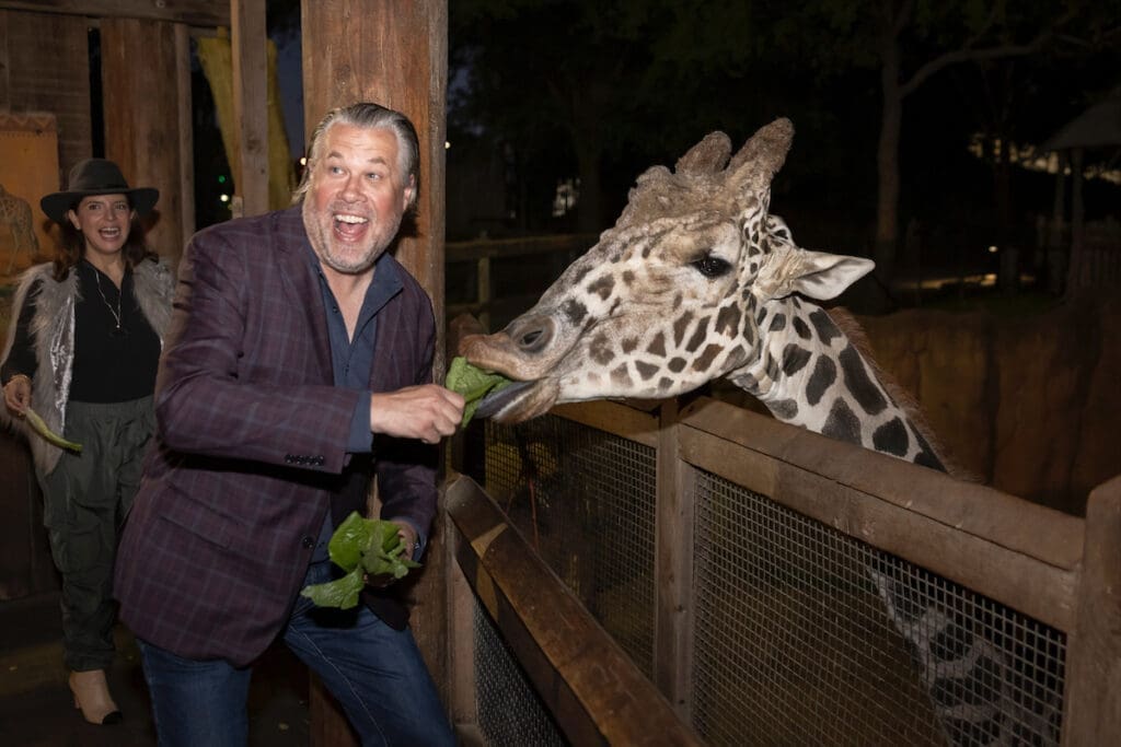 Kevin Sullivan feeding the giraffe at the 2023 Zoo To Do. (Photo by Thomas Garza and Rob Wythe/Wythe Portrait Studio)