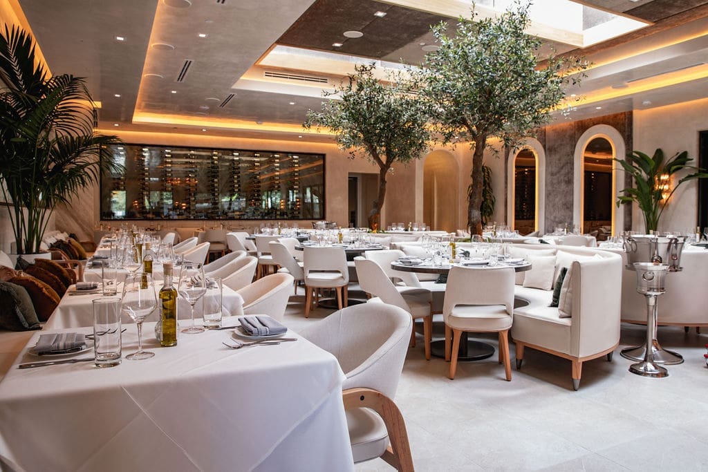 The elegant interiors of Lombardi Cucina are bathed in shades of ivory with cozy demi-lune style sofas pulled up to white cloth-covered tables illuminated by Venetian glass chandeliers.