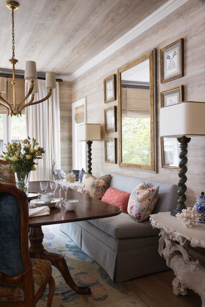 In the dining room, the walls are covered in French Elitis faux bois wallpaper from George Cameron Nash. Custom Kisabeth Furniture banquette. Antique table from the homeowners’ collection. Visual Comfort chandelier. Vintage Minton-Spidell chairs. Abrash rug. (Photo by Emily Minton Redfield)