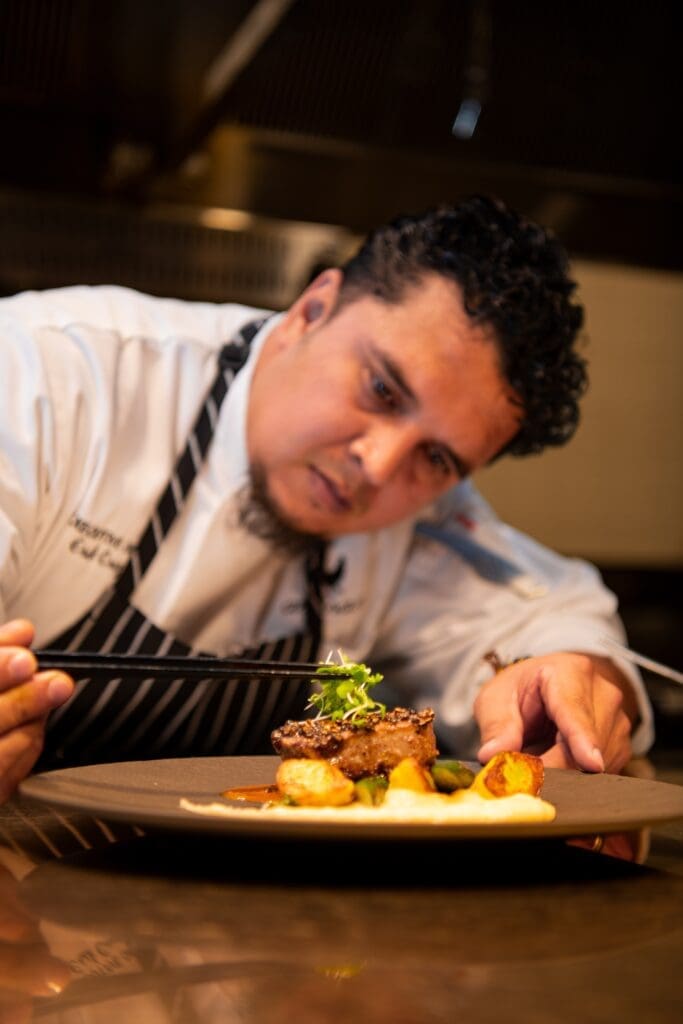 Executive chef Erik Cruz puts the finishing touches on a dish at the newly relocated restaurant, Artisans in The Houston Galleria area. (Photo by  Shane Dante)