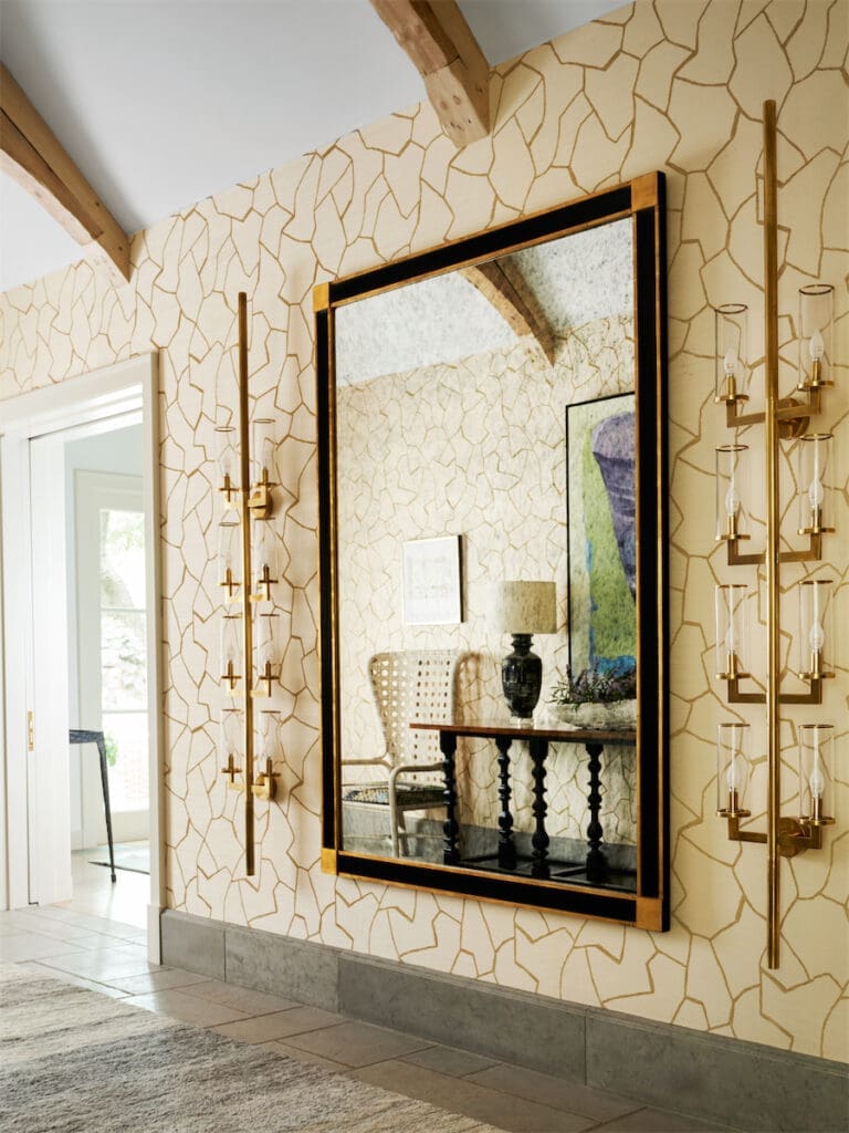 A vignette in the entry includes a custom mirror and muscular Kelly Wearstler sconces from Visual Comfort. Donghia wallpaper. (Photo by Stephen Karlisch)