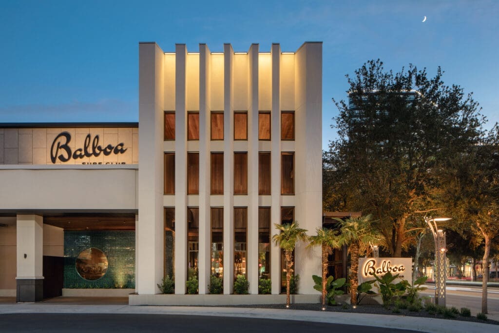 Design inspiration for the Balboa Surf Club space draws from the Brazilian brutalist style, seen in the towering facade and dramatic entryway, and the '70s surf bungalow, as evidenced by the abundance of tropical plants and handmade, colorful tile. 