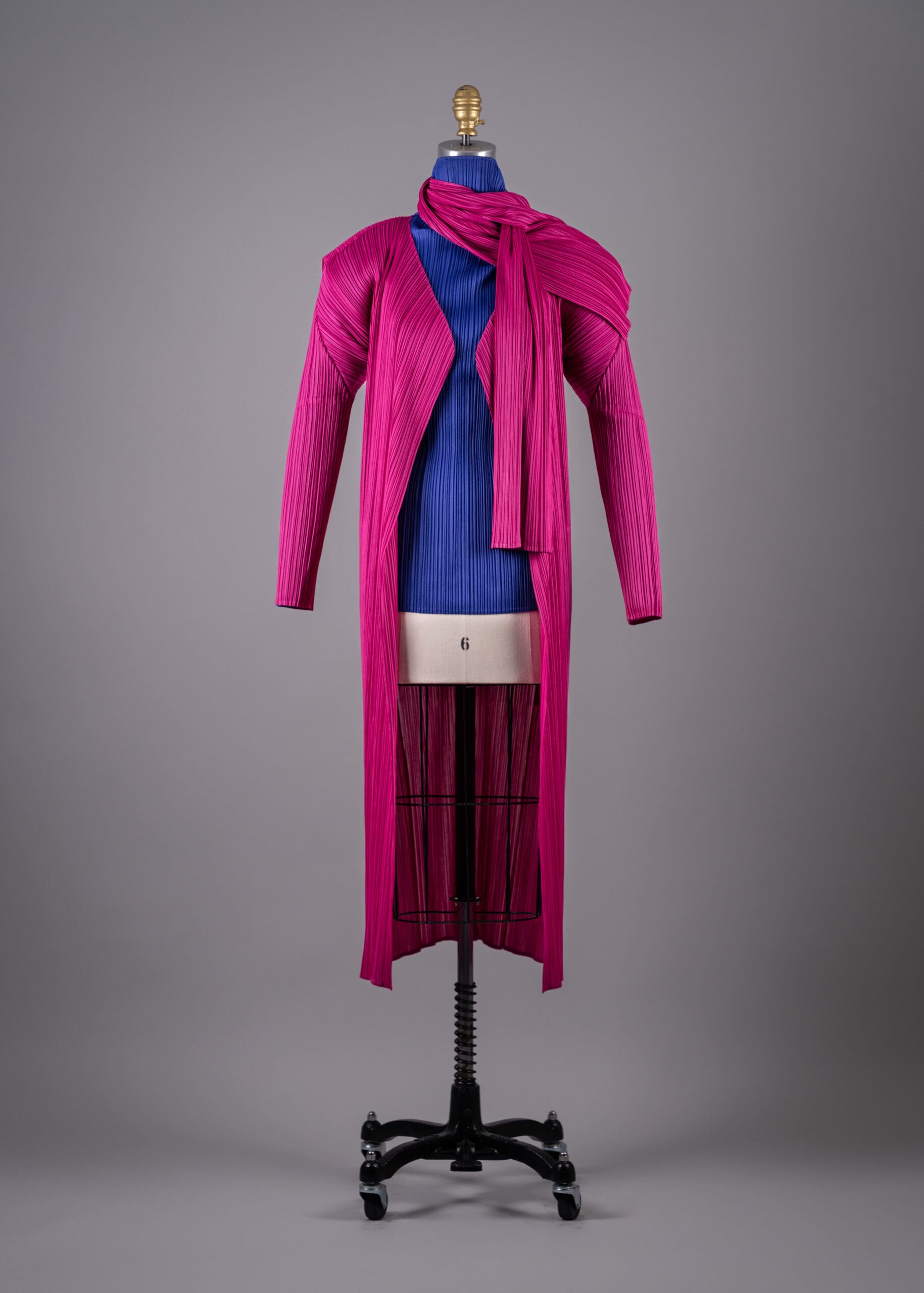 Issey Miyake's violet-blue polyester pleated turtleneck top with pink polyester pleated coat and scarf (Photo by Shane Quereshi)