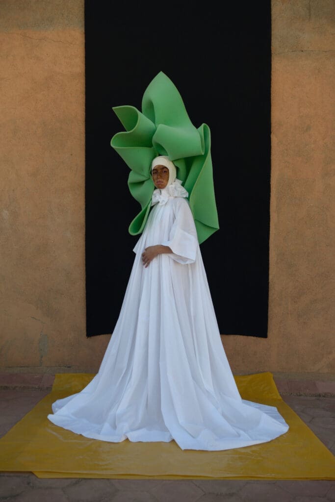 Model in a white caftan with green
headdress by @artsimous, 2021. (Courtesy @artsimous 2021)