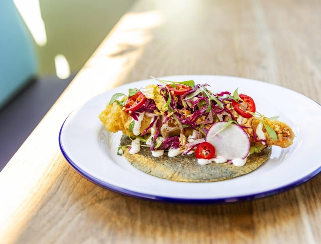 Cradled in those warm, tender corn tortillas you’ll find a variety of tacos like the crispy fish taco ($7), a wink to the English-born fish and chips with a puree of pea and avocado, pickled fresco chiles, shaved breakfast radish and a squeeze of lime crema. (Photo by Julie Soefer)