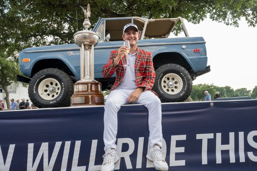 2023 winner Emiliano Grillo sips champagne seated next to the Leonard Trophy.