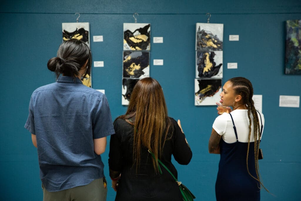 Three art enthusiasts discuss Pooja Taneja's fluid "Dance of Life" series. (Photo by Derik J. Mercado)