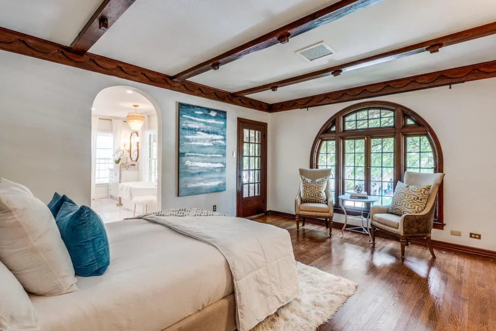 The primary bedroom's arched windows offer treetop views of the quiet Highland Park street. 