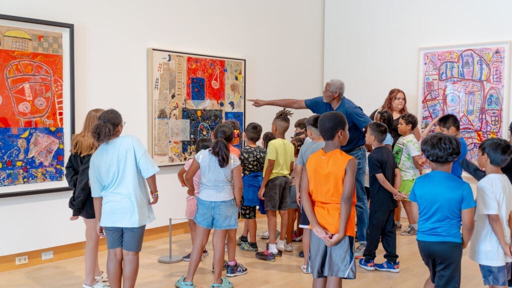 Floyd Newsum discusses his artwork with young visitors at the Madison Museum of Contemporary Art in conjunction with his 2023 solo retrospective, "Evolution of Sight." (Courtesy MMoCA)