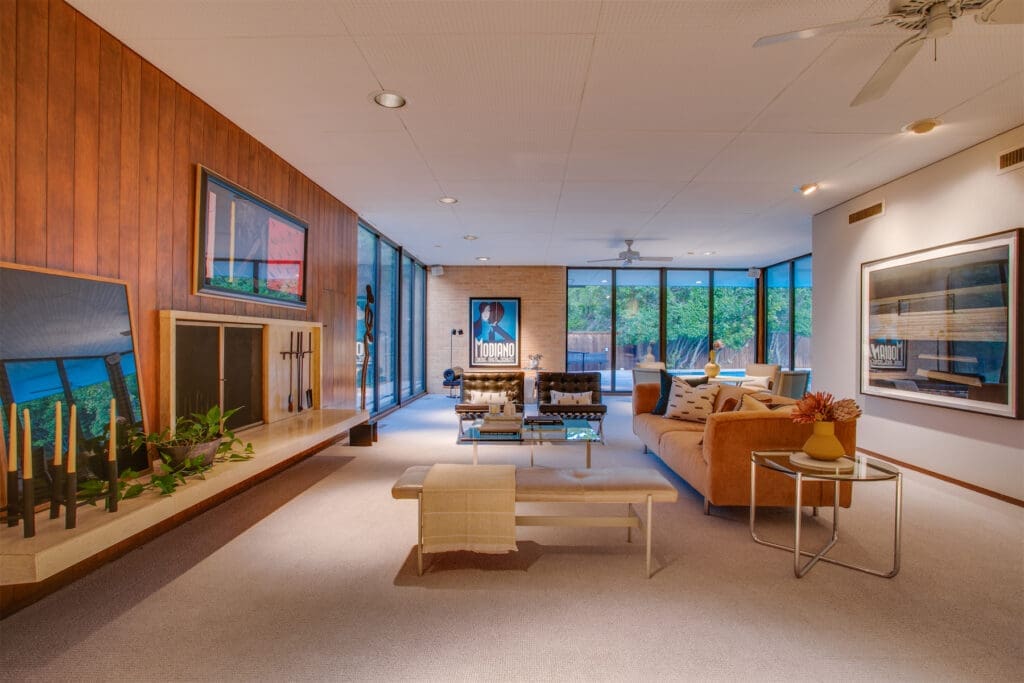 Another spacious living area with custom cabinetry, wood-paneling, and floor-to-ceiling windows. 