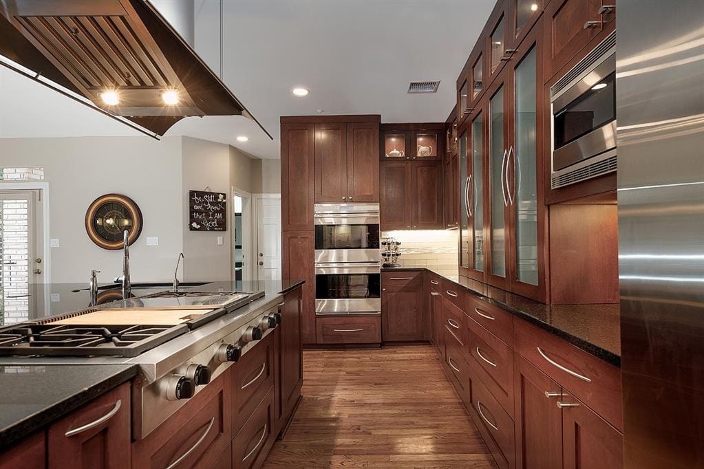 The kitchen features custom cabinetry, professional Wolf appliances, and granite countertops. 
