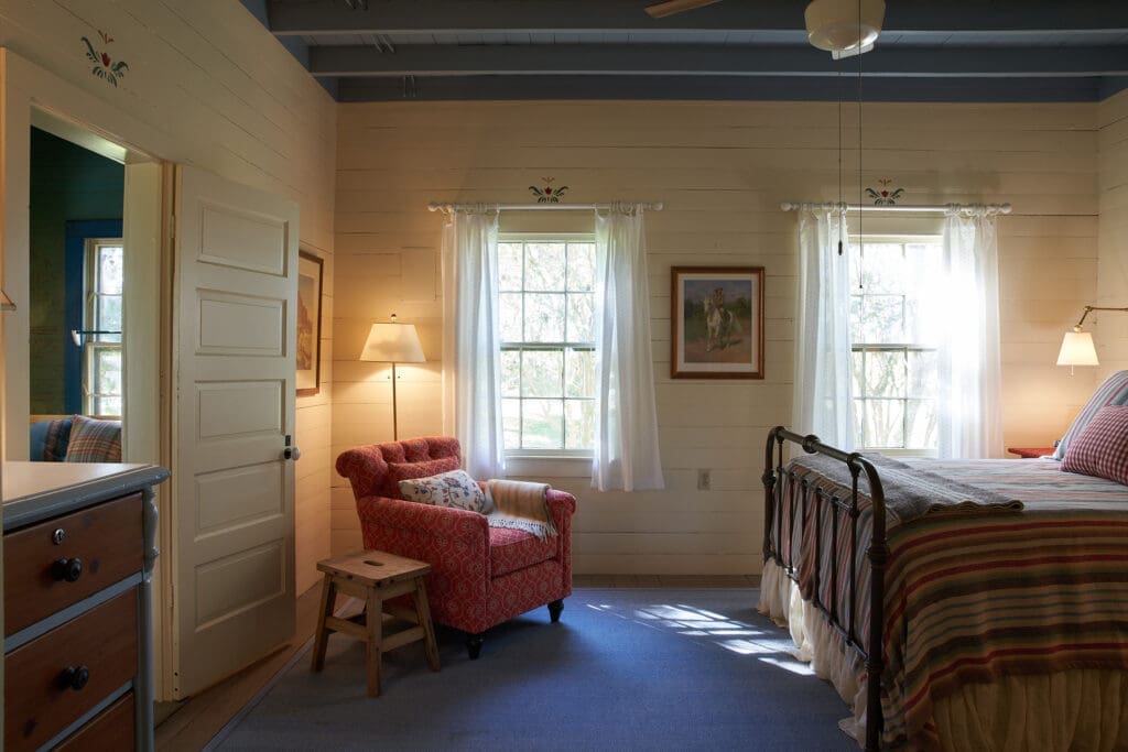 The main bedroom has rustic
finishes and decorative painting
above the doors. The exposed joist ceiling was painted blue. (Photography Pär Bengtsson)