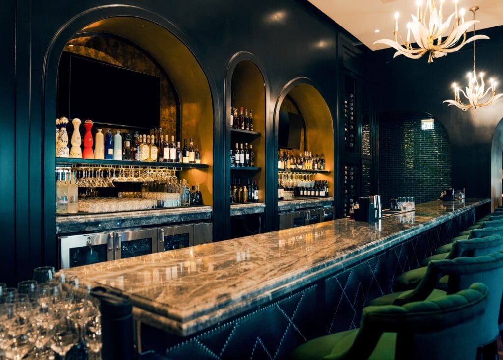 One enters Leo's through the bar, which reveals shallow Chesterfield sofas beneath the windows, teetering bar stools upholstered in plush emerald velvet, and a misty, moody abstract mural. (Photo by Corey Watson)