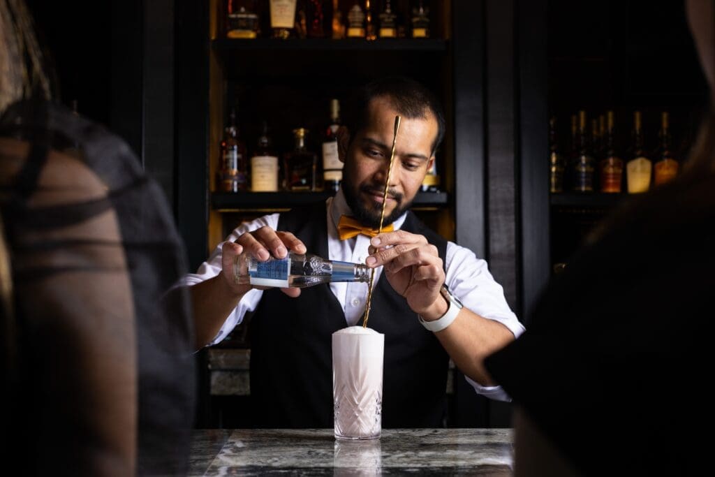 Signature cocktails or classics are artfully prepared. The tincture Strawberry Fields blends strawberry lemongrass-infused vodka with yuzu juice and fresh ginger-spiked syrup, while the Lavender Haze (shown) is a gin and cassis sour enriched with cream and egg-white foam. (Photo by Andrew Hemingway)
