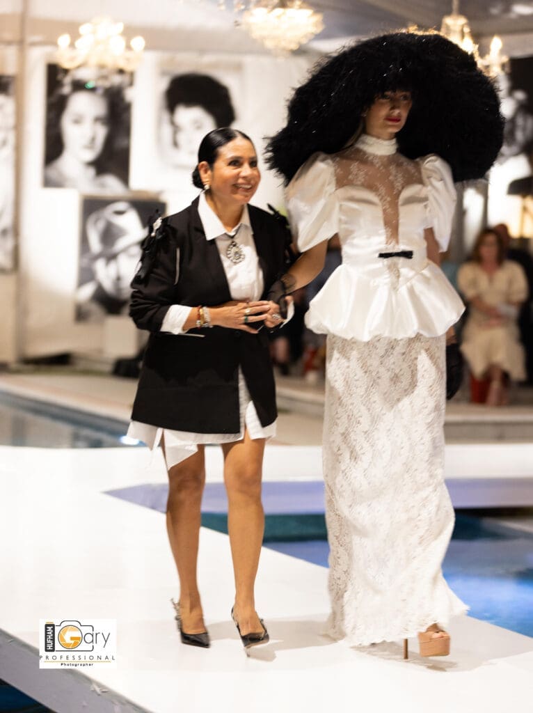 Los Angeles-based designer  Maribel Julcahuanca walks the runway with one of her models at "Fashion Woodlands" at the home of Theresa Roemer.