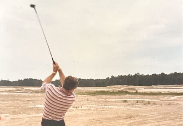 Earl Higgins hits a shot off the first golf course in The Woodlands before the grass is even put in.