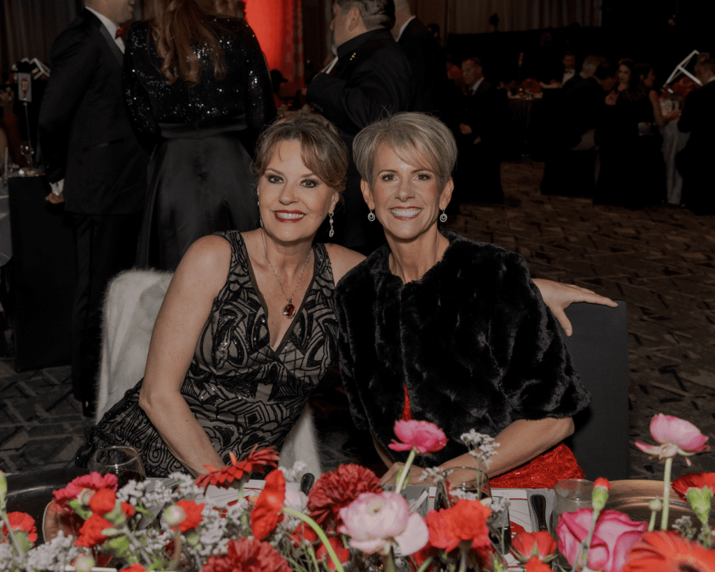 Jill Barber and Mari Harvey enjoy a moment at their table during the Heart Ball at The Woodlands Waterway Marriott. (Photo by 209 Photobooth Company)