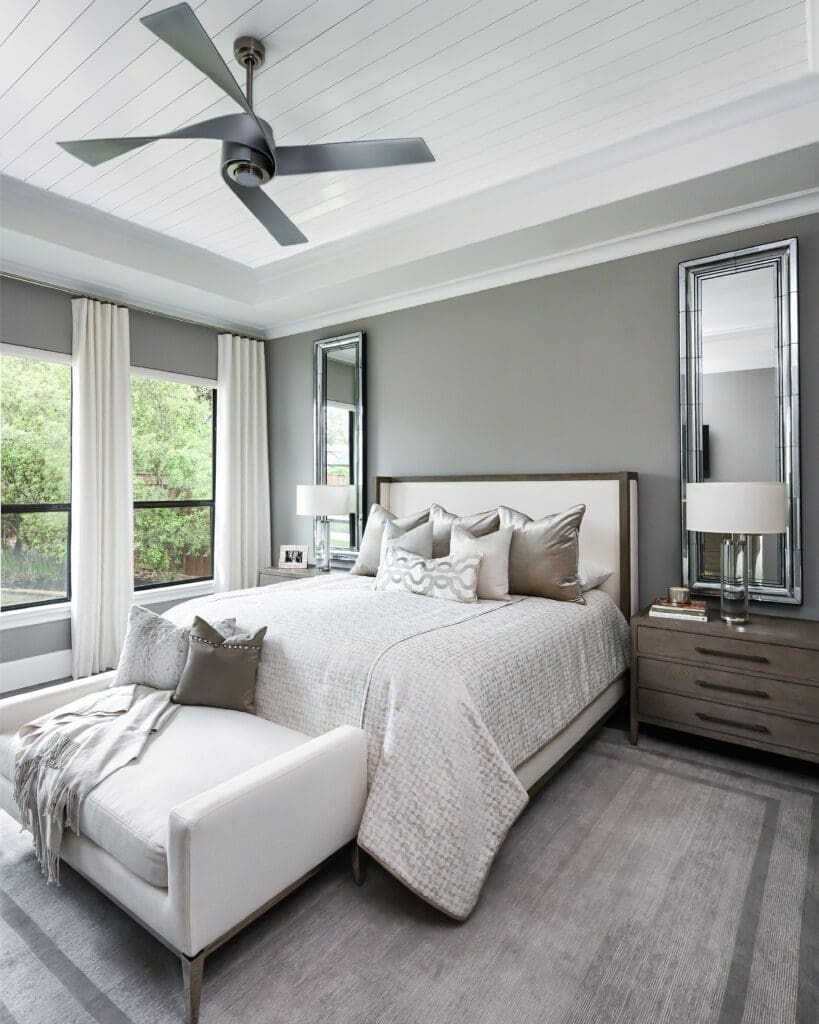 The primary bedroom features minimal window treatments, allowing full views of the backyard. (Photo by Charbonneau Interiors)