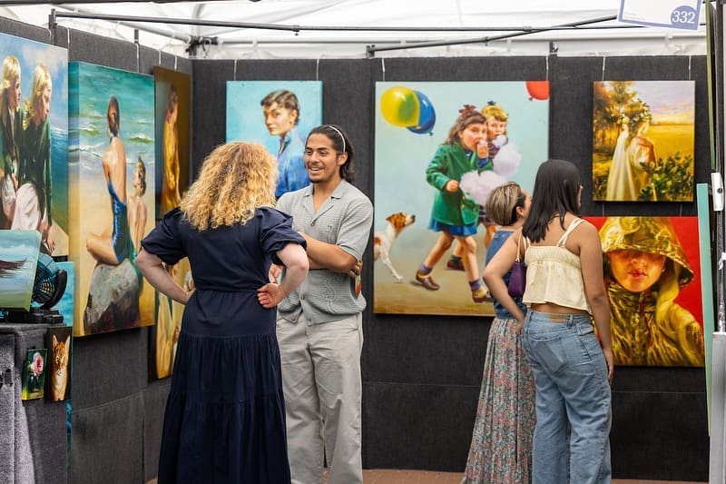An artist and festivalgoer share a moment at the booth during The Woodlands Waterway Arts Festival. (Photo courtesy The Woodlands Arts Council)