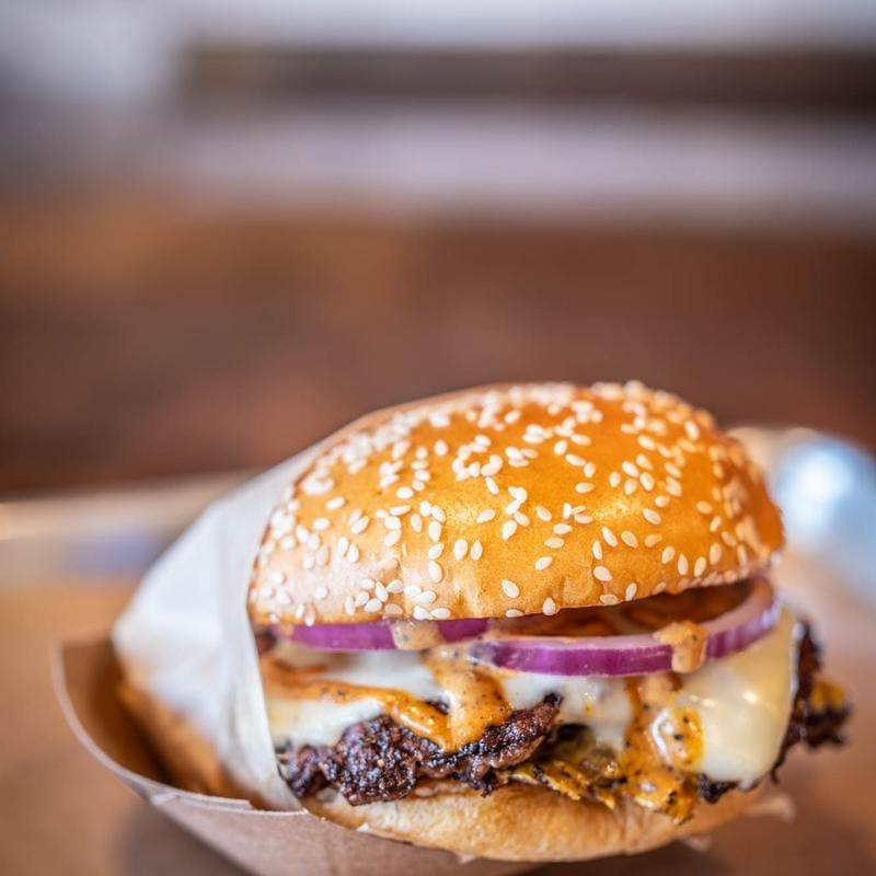 Dayne’s OG Burger brings serious flavor with double patties made from brisket trimmings, American cheese, red onion, and Loven Sauce on a garlic-buttered sesame bun. (Courtesy)