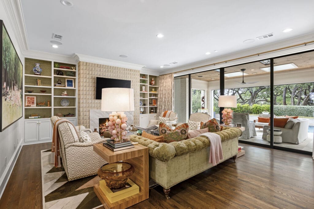 The main living room at 1128 Shady Oaks Lane opens directly to the pool and patio, combining plush seating, custom millwork, and a soft blend of color and texture curated by Maven Interiors. (Freeze Media)