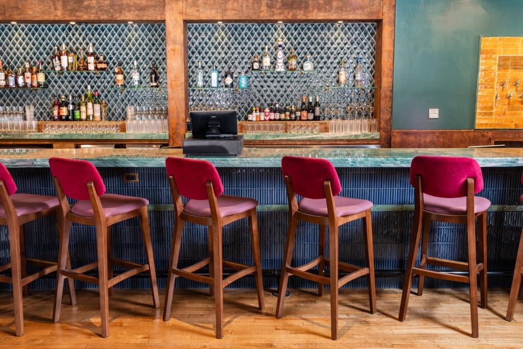 The bar area inside Good God, Nadine's features a bar wrapped in tile lit with brass accented lighting. (Photo by Becca Wright)