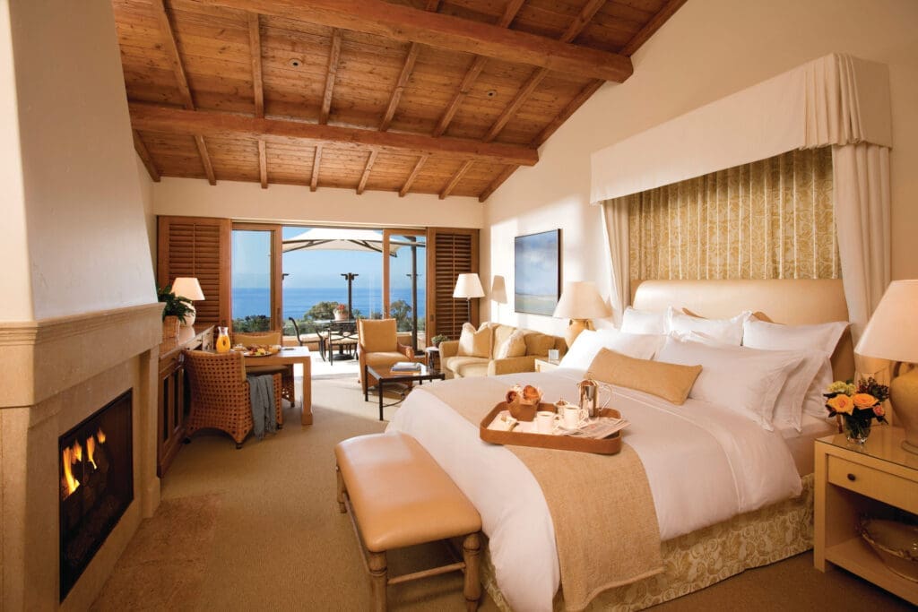 Well-appointed bungalow rooms include a wood beam ceiling, a fireplace framed by Italian limestone, and a deep soaking tub, as well as a private terrace. (Photo by The Resort at Pelican Hill)