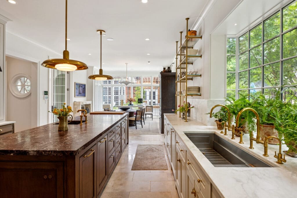 In addition to the custom cabinetry and brass shelving, the kitchen showcases an oversized Rosso Levanto marble island and a stunning La Cornue range. (Photo by Full Package Media / Compass)