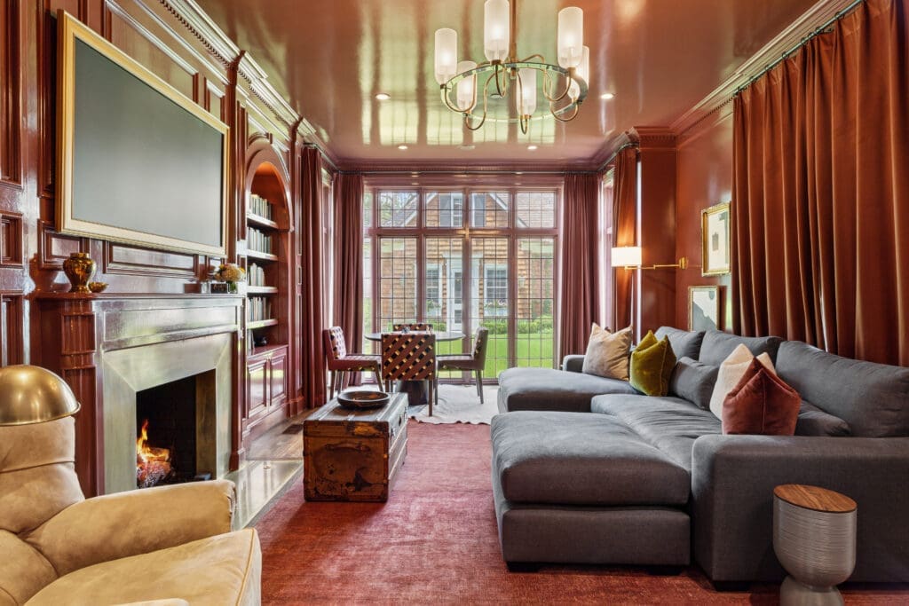 The red lacquered library features custom millwork and a burnished brass surround. (Photo by Full Package Media / Compass)