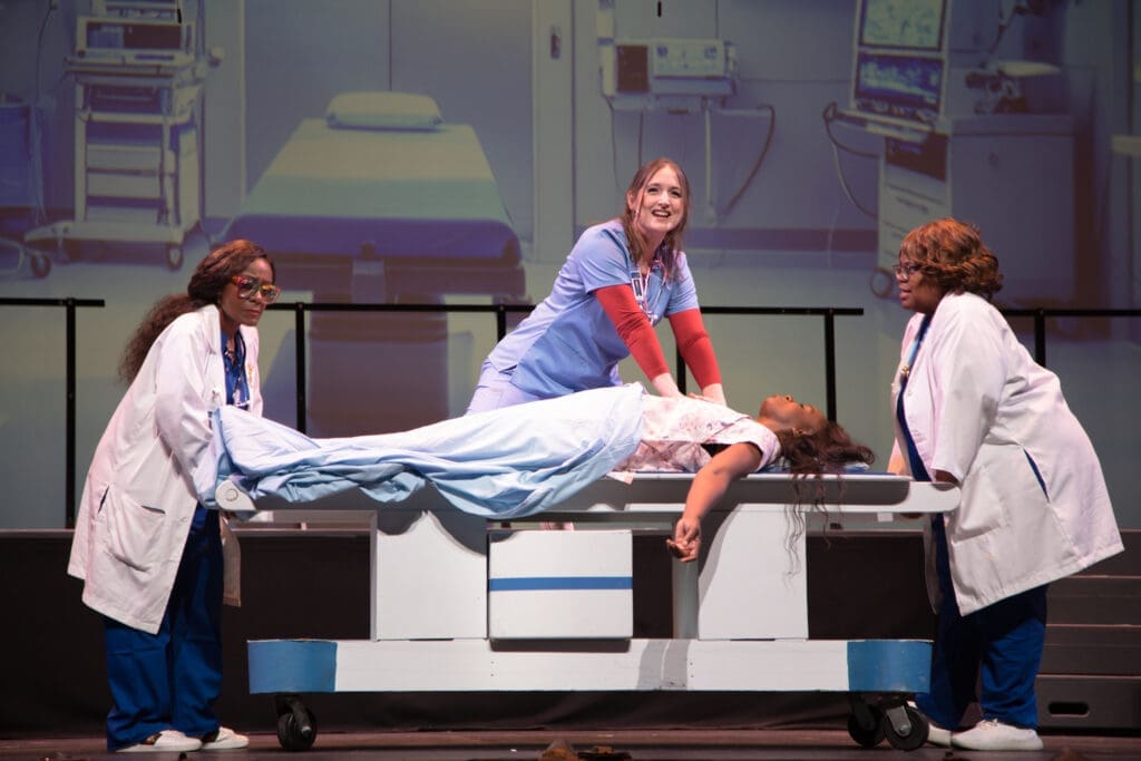 Uchenna Paul as Dr. Scholls, Bri Holcombe as Dr. Meredith Grey, Elizabeth “Peaches” Lockett as Dr. Miranda Bailey and Michelin Charles as patient in Night Court's "Law’s Anatomy: The Juris Doctor Will See You Now" (Photo by Ricornel Productions)