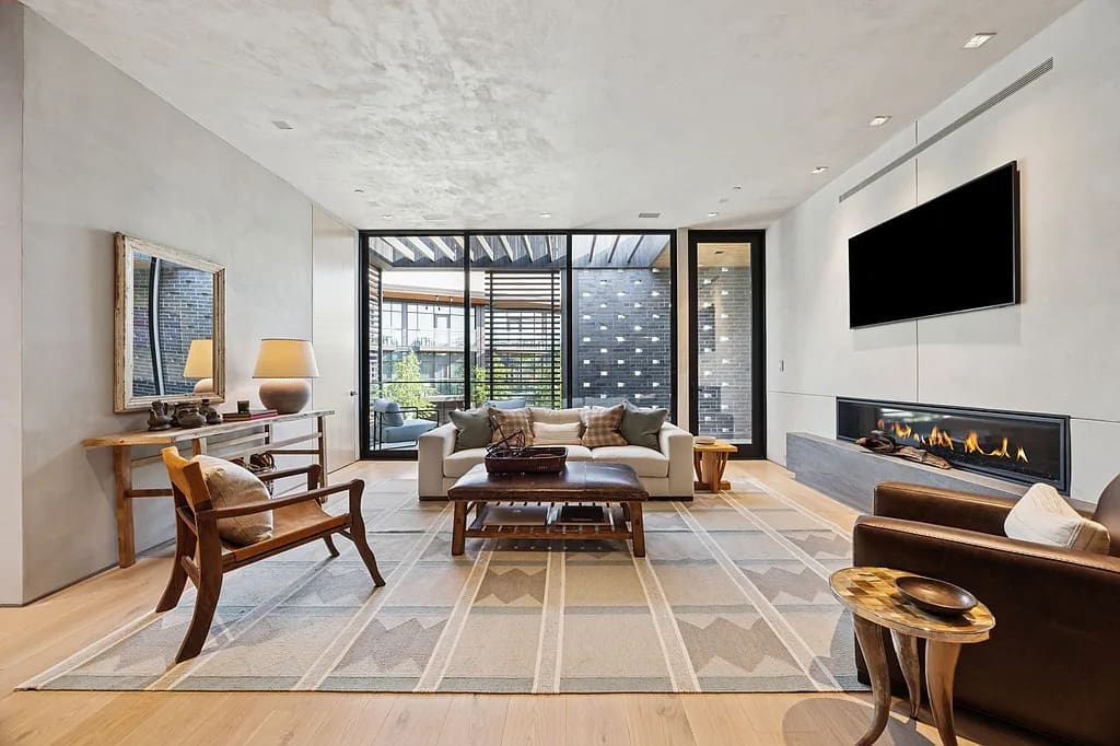 A spacious living room with fireplace opens to private terraces, balancing comfort with sophistication. (Courtesy)