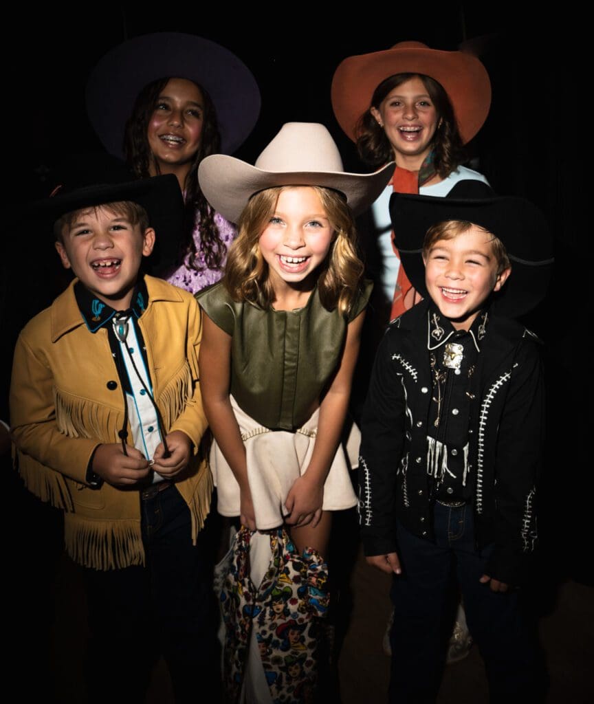 The kids stole the spotlight, laughing backstage before hitting the runway in bright Western outfits. (Photo by Avin Park Photography)