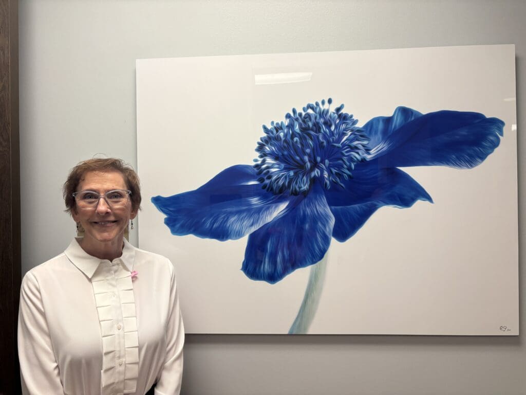 Patti Gary stands with her floral photograph at the Melissa Preston Breast Center at Memorial Hermann The Woodlands. (Photo by Laura Landsbaum)