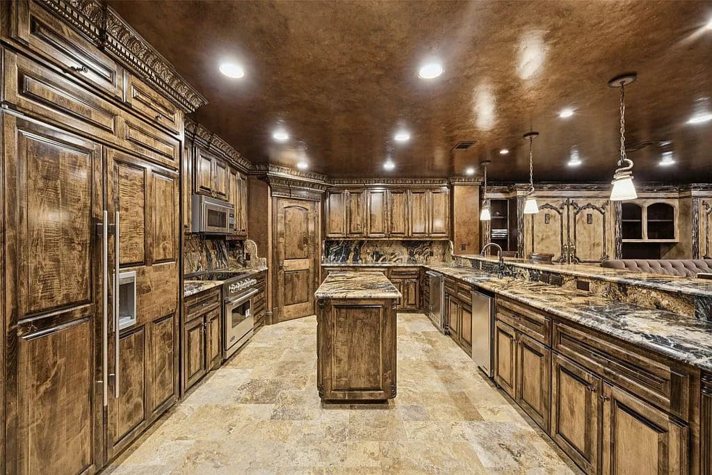 The main kitchen combines rich wood cabinetry with granite counters and commercial-grade appliances, one of two full kitchens designed for entertaining. (Courtesy)