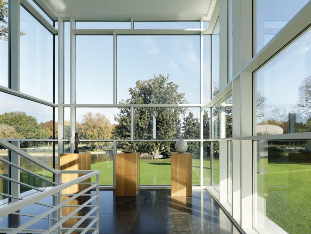 The house features a glass-enclosed stairwell, floor-to-ceiling windows, a double-height living room, and a suspended study overlooking the grounds. (Photo by JA2 / Compass)