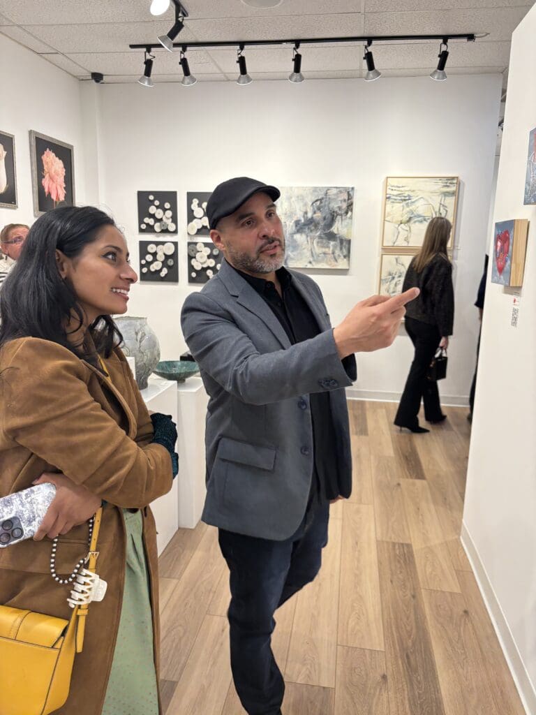 Cruz explains that each image has an accompanying QR code that allows viewers to see the art in motion. (Photo by Laura Landsbaum)