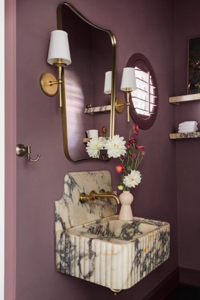 A color drenched powder room with a unique mirror and sink bring drama to a small space. (Photo by Madeleine Harper Photography)