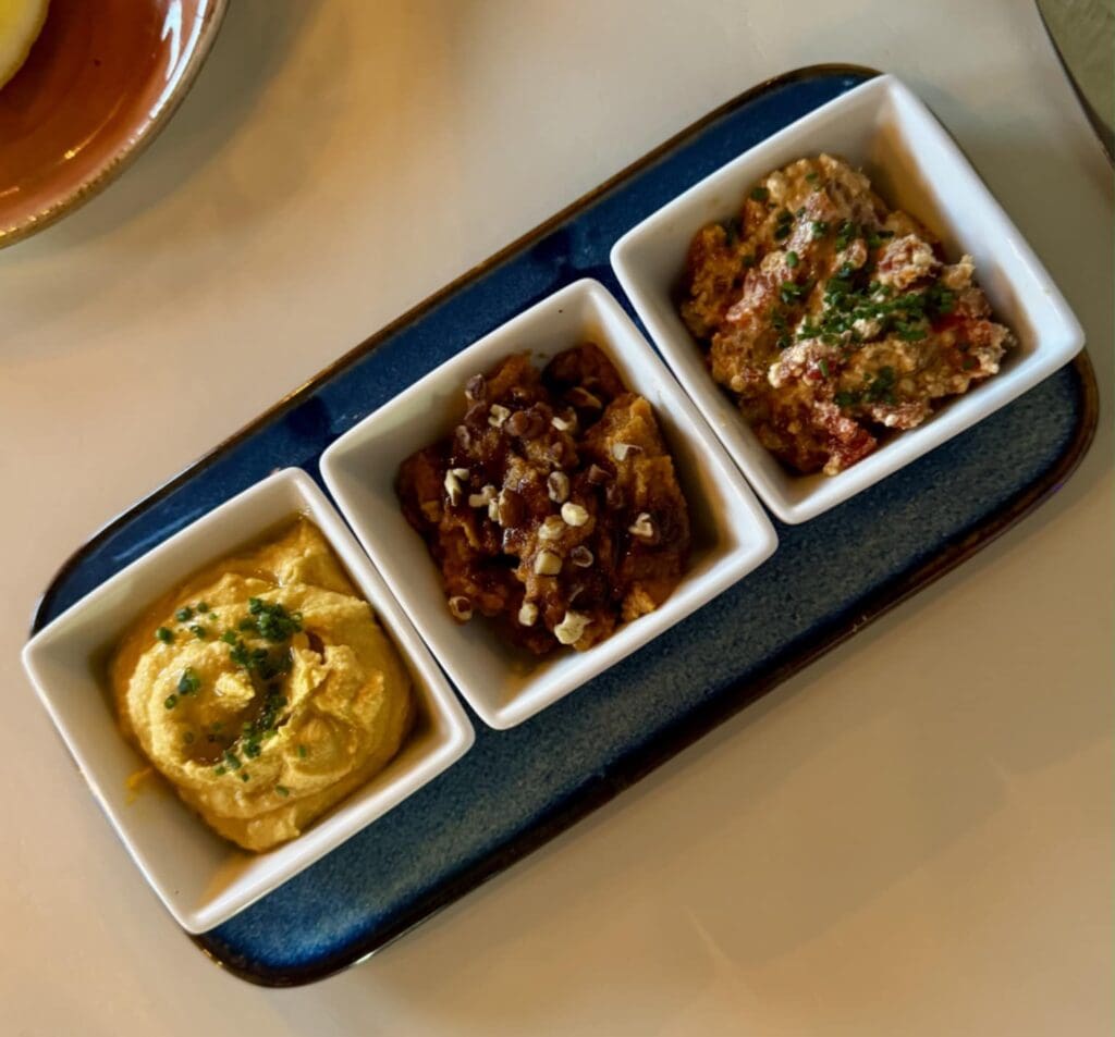 The Meraki dip sampler — classic hummus, muhammara, and htipiti — came served with fresh-baked pita. (Photo by Walt Burns)