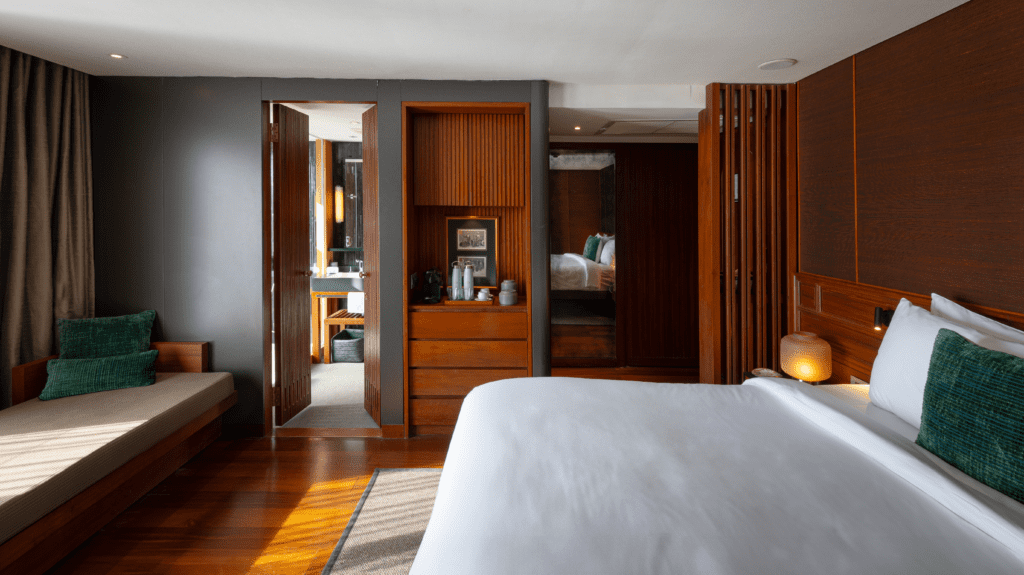 Warm wood and dark stone details define the Aqua Mekong suites, each with floor-to-ceiling windows and a private terrace overlooking the river. (photo courtesy of Aqua Expeditions)