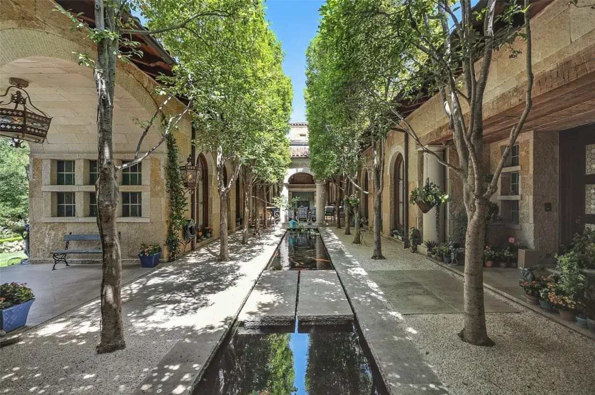 A tree-lined courtyard centered on a long reflecting pool showcases 6236 Indian Creek Drive's Mediterranean-inspired design. (Courtesy)
