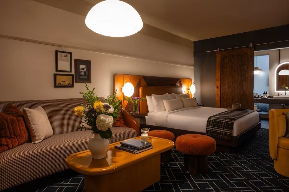 Guest suites blend olive green, warm wood tones, leather accents, and geometric flooring with mid-century-inspired furnishings. (Courtesy)